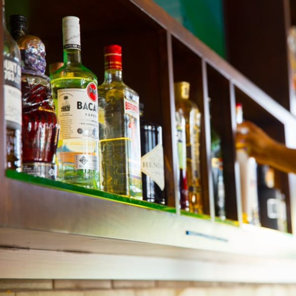 Bottles of liquor, including Bacardi, on a lit shelf at Aro Latin's bar.