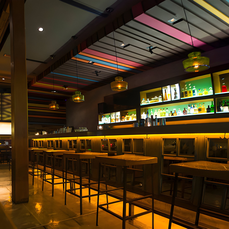 Aro Latin's bar area with high-top tables, stools, and a colorful ceiling, illuminated by warm lighting.