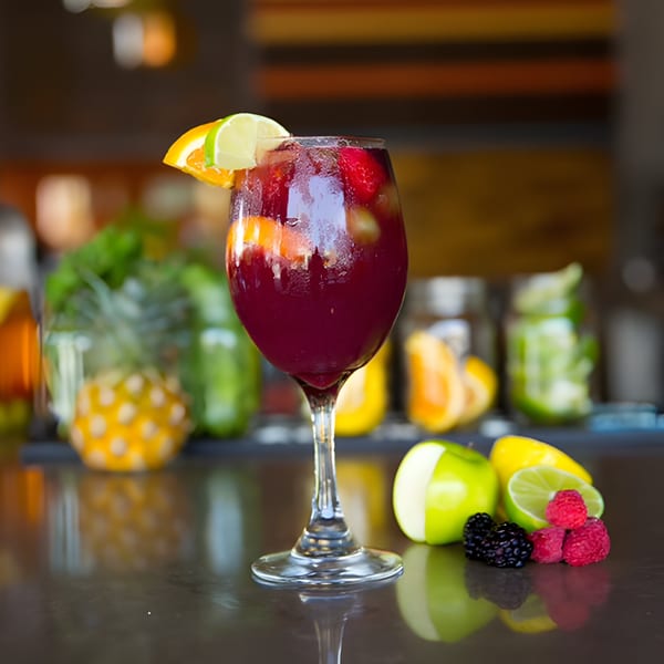 Aro Latin's red sangria with fruit garnishes, including orange, lime, raspberries, and blackberries.